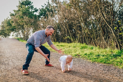 Un père apprend à marcher à son enfant. L'égalité femmes-hommes illustrée dans l'éducation des petits et petites.